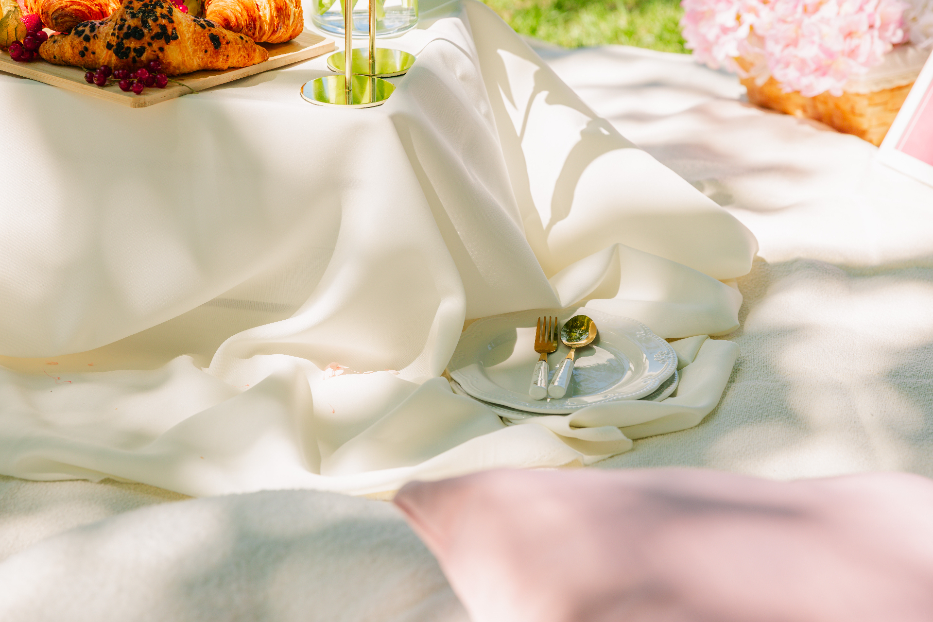 Soft cream drapery with vintage plates and gold cutlery in dappled sunlight