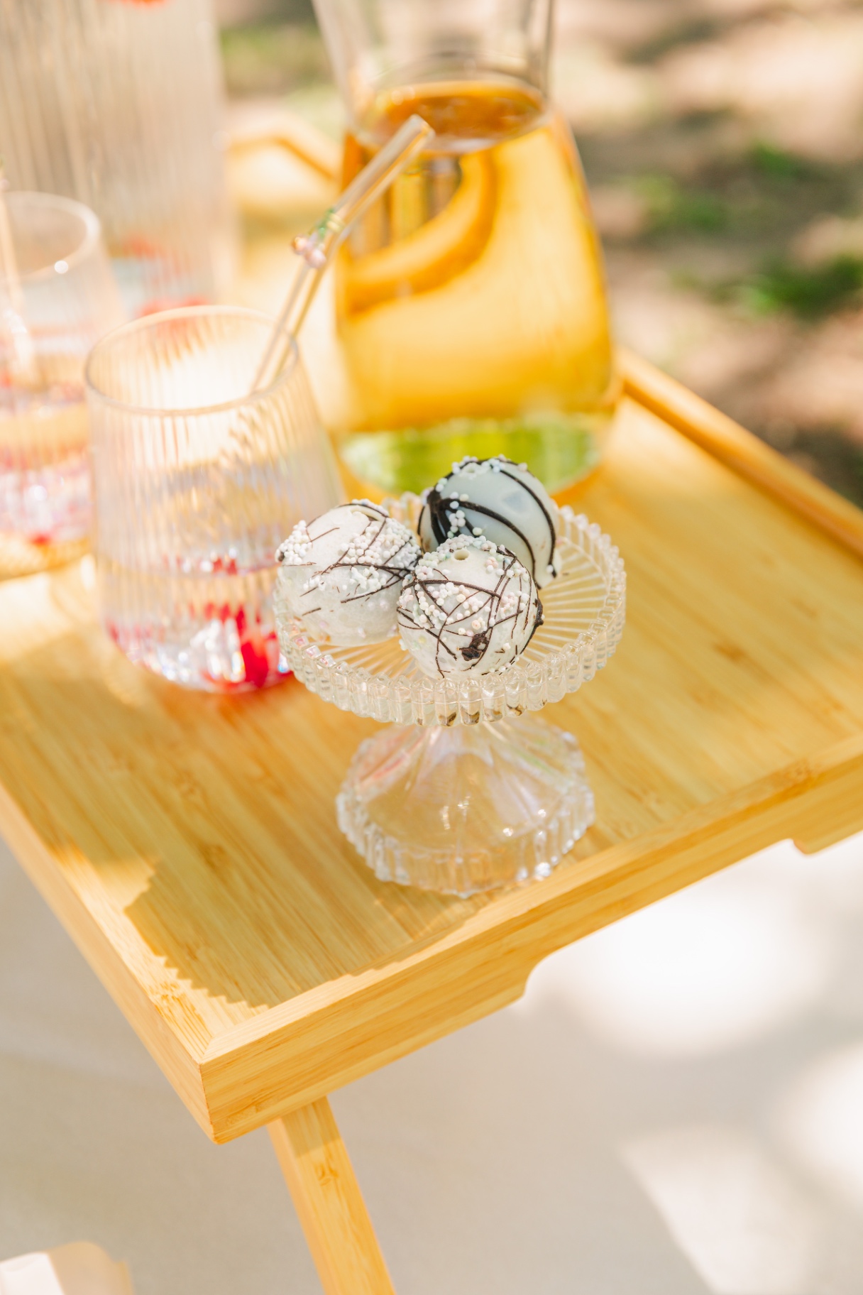 Coconut truffles on a crystal stand with ribbed glasses and amber pitcher