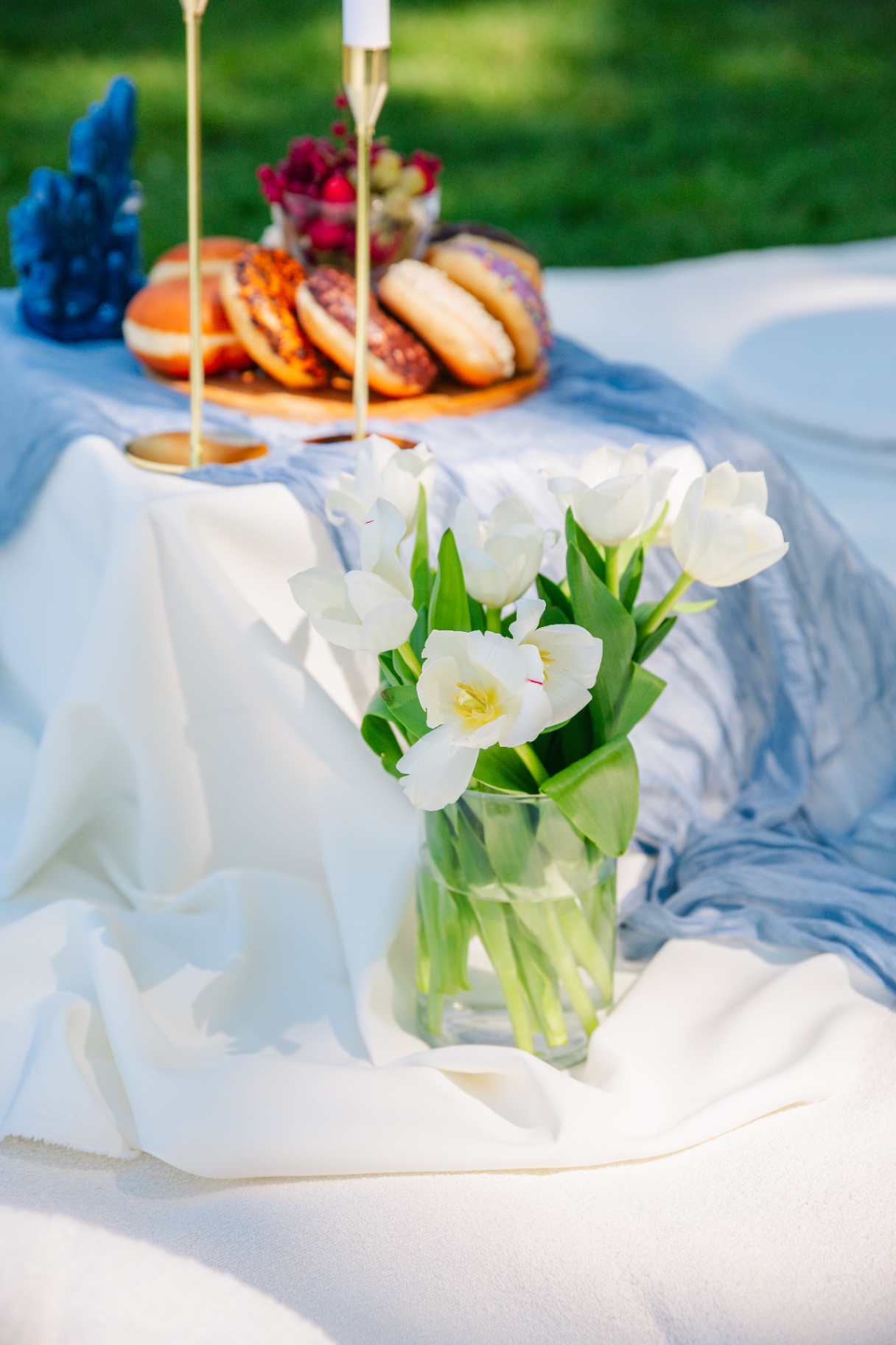 White tulips in glass vase with blue gauze runner and donut platter