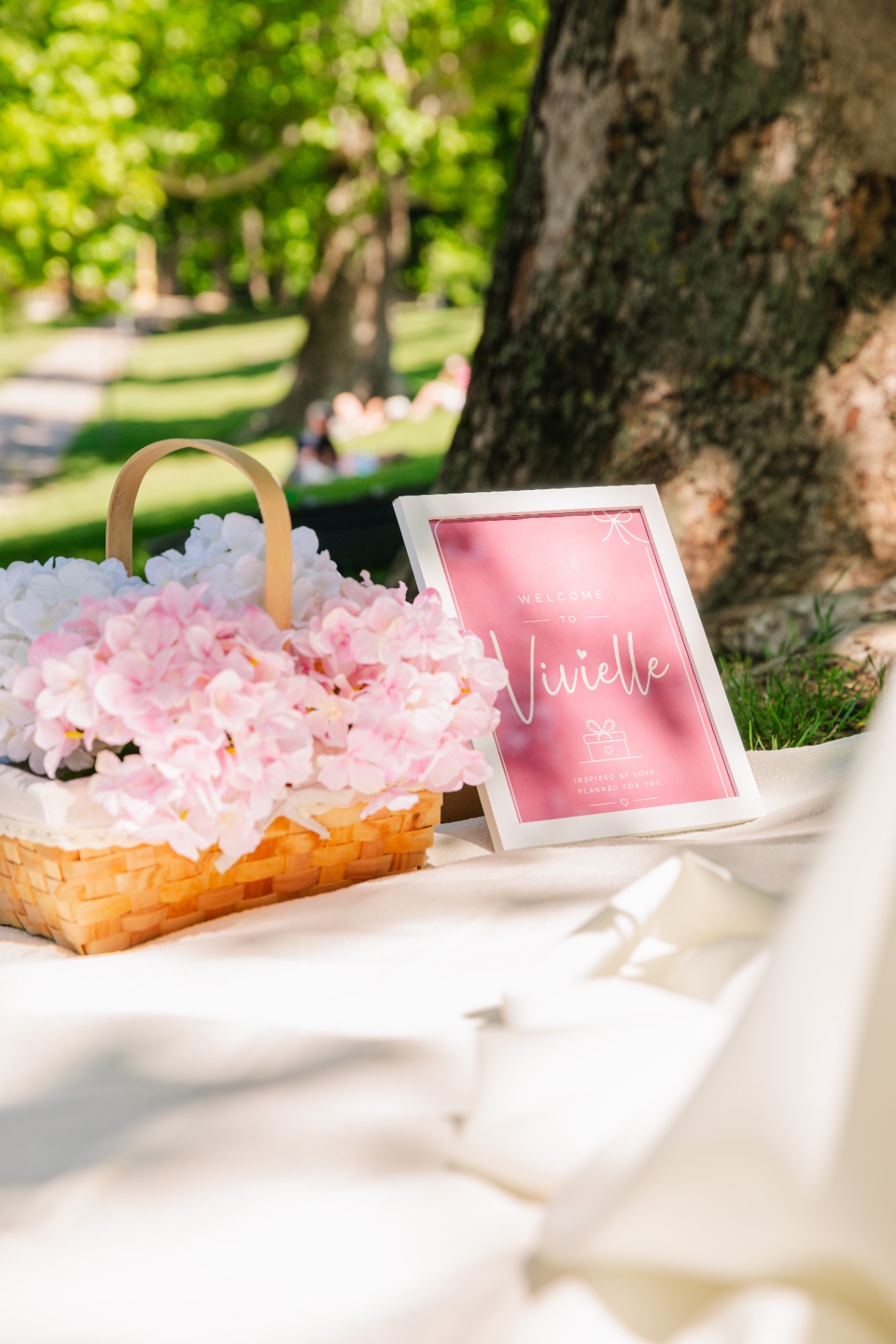 Pink hydrangea basket beside a Welcome to Vivielle sign in the park